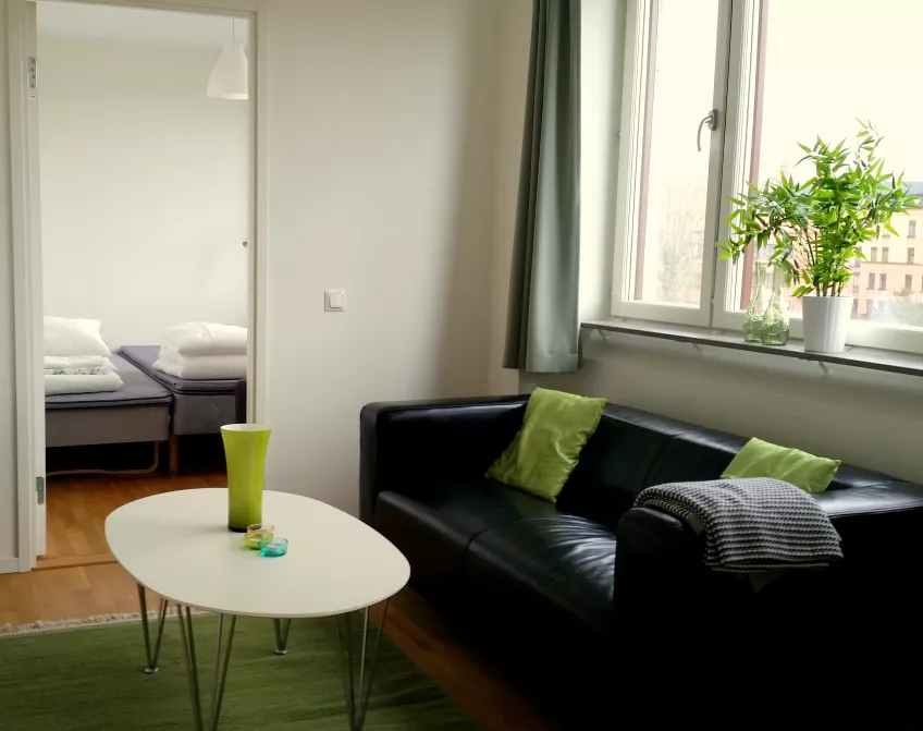 A view of the living room in an apartment at the housing area Folkets park, with a sofa and coffee table, and a bedroom in the background (picture).