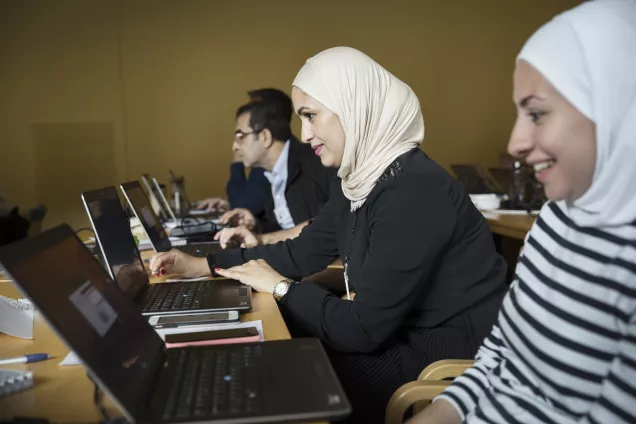 Three people in a row seated in front of open laptops. Photo by Johan Bävman.