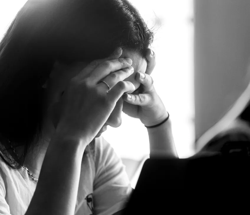 Student covering their eyes with their hands. Black and white photo by Kennet Ruona.