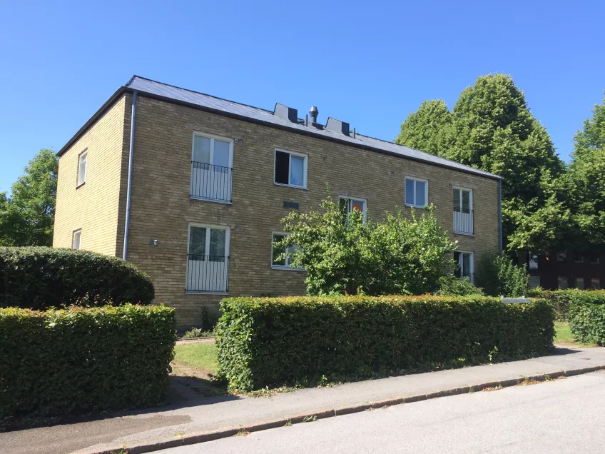 The exterior of Gerdagatan 13, a two-storey building with a lawn and a hedge in front (picture).