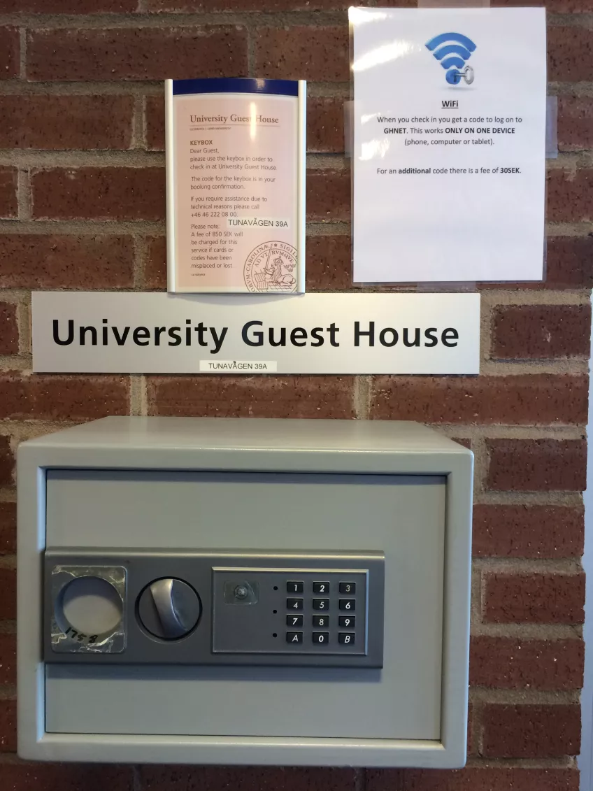 A small grey key safe mounted on a red brick wall, for collecting keys. Photo by LU Accommodation.