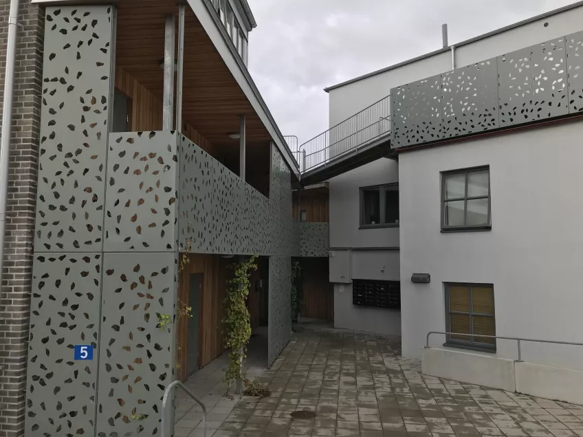 View of an entrance at the nexus of two buildings, the left one wooden with metal railings, the right one white. Photo by LU Accommodation. 