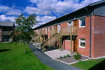 An overview of some of the buildings at Kulgränden showing one of the buildings to the right and a lawn to the left (picture)